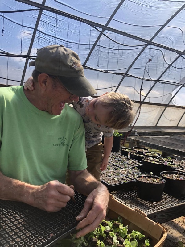 Owner of Doris Greenhouse tending seedlings with grandchild — family-owned greenhouse in Greenwood, SC